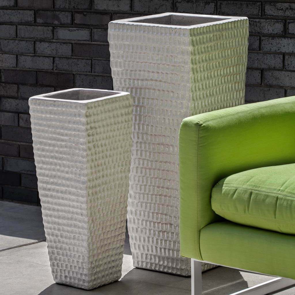 Set of two tall square dimpled planters in antique white beside a modern green chair