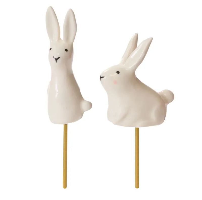 A miniature whimsy white ceramic rabbit that is on a golden colored stick that can plucked into a plant arrangement