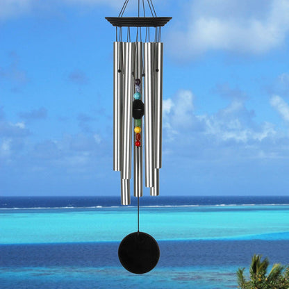 Wind chime with colorful stones against a blue sky and ocean background