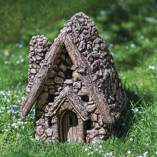 Decorative fairy house on grass with a blurred natural background